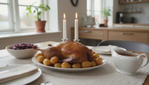 Stegt and på fad med kartofler, rødkål og brun sovs på et dækket bord