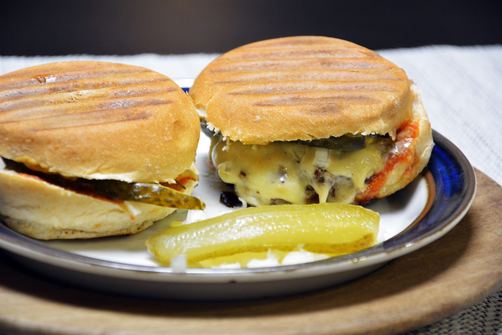 To hjemmelavede cheeseburgere med grillstriber på bollen, smeltet ost og syltet drueagurk på en tallerken