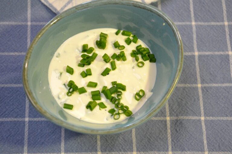 Creme fraiche-dressing med purløg i en turkis skål på et blåternet viskestykke