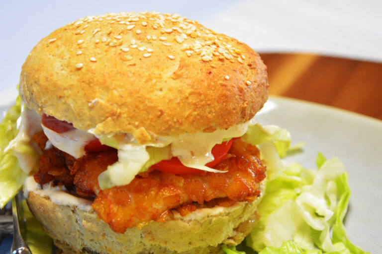 Crispy chicken burger med sprød paneret kylling, tomat, salat og chilimayo i en sesamdrysset burgerbolle