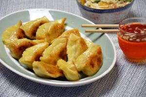 Hjemmelavede dumplings med sprød bund stegt på panden, serveret med dip