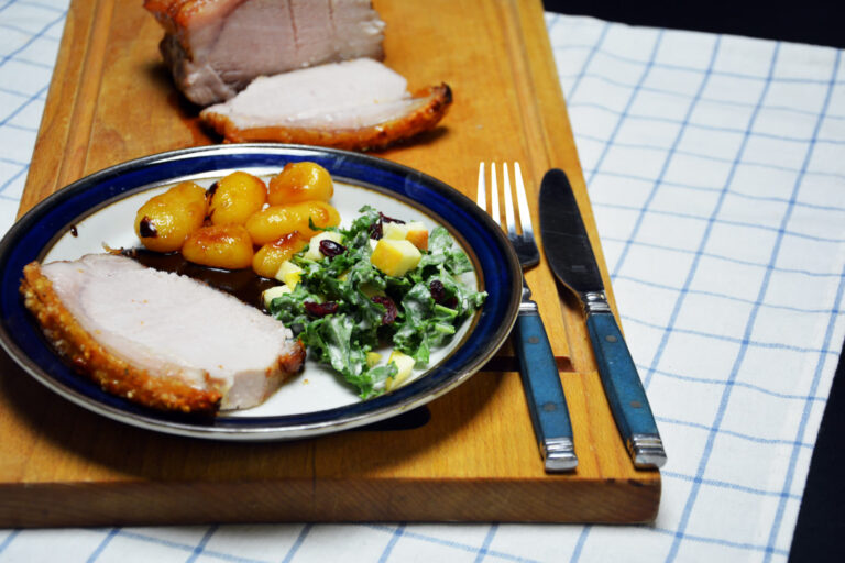 Flæskesteg sous vide skåret i skiver med sprød svær, serveret med brunede kartofler, brun sovs og grønkålssalat