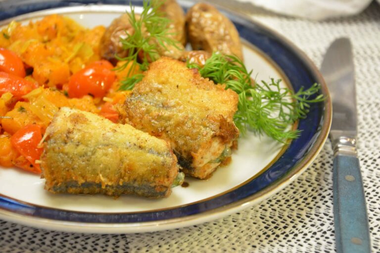 Stegt hornfisk i gyldne stykker på en tallerken med blå kant, serveret med sauteret hokkaidogræskar, cherrytomater, dild og råstegte kartofler